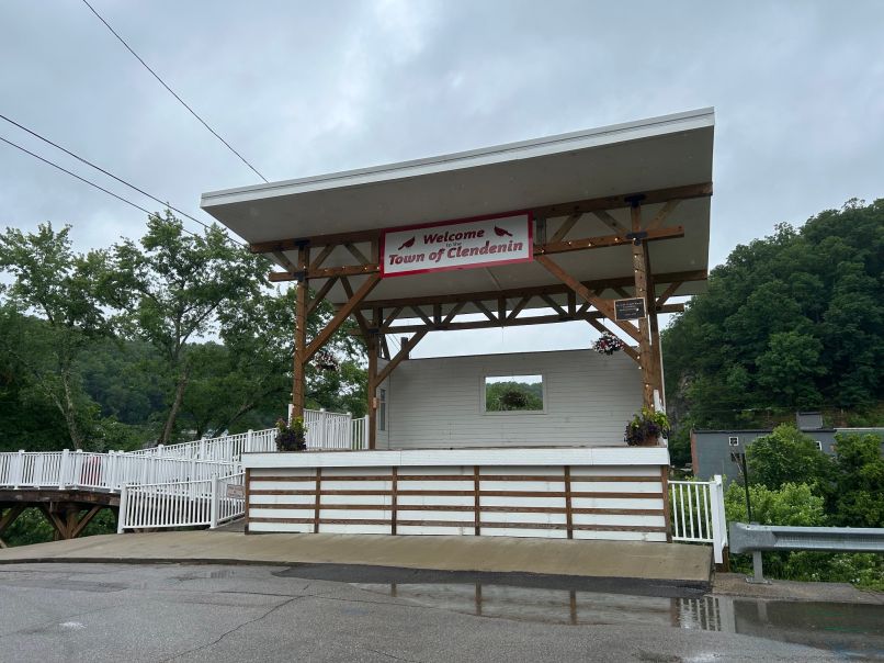 A stage with a sign that reads Welcome to the Town of Clendenin sits at the end of a street with mountains visible in the background.