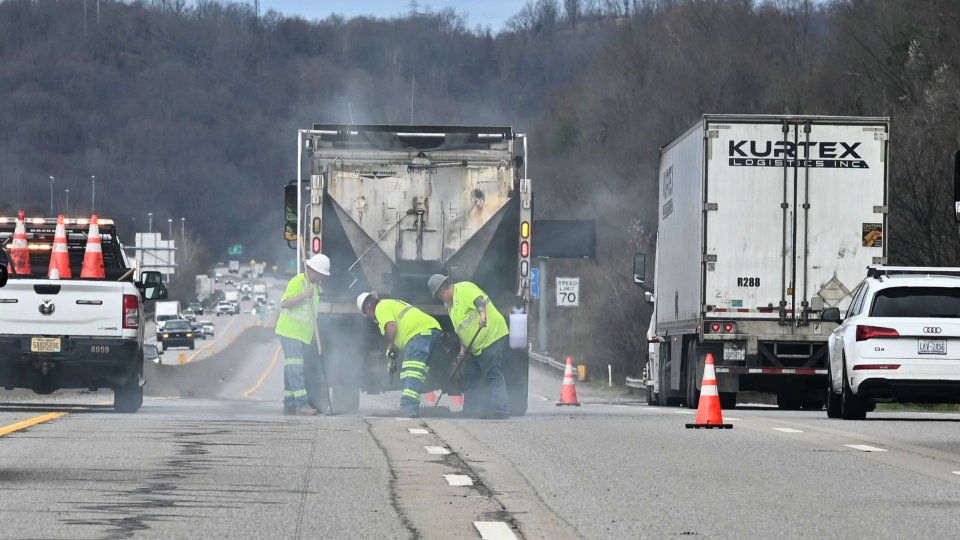 DOT workers are seen on an Interstate roadway with traffic passing on the left and right lanes.